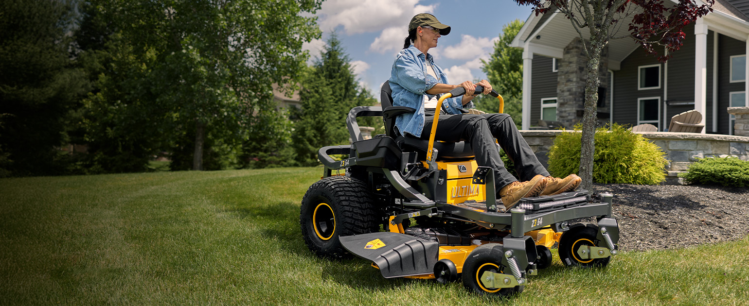 woman on cub cadet zero-turn mower cutting grass