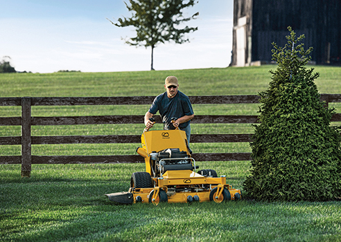 man cutting around flower bed with commercial walk-behind mower