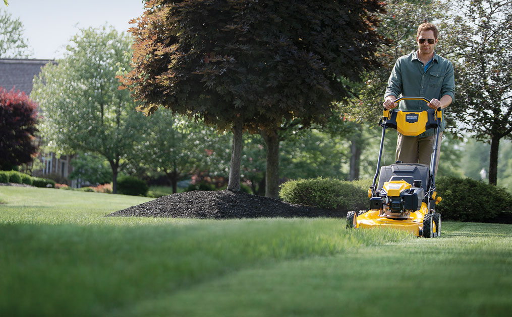 man cutting his lawn with walk-behind mower