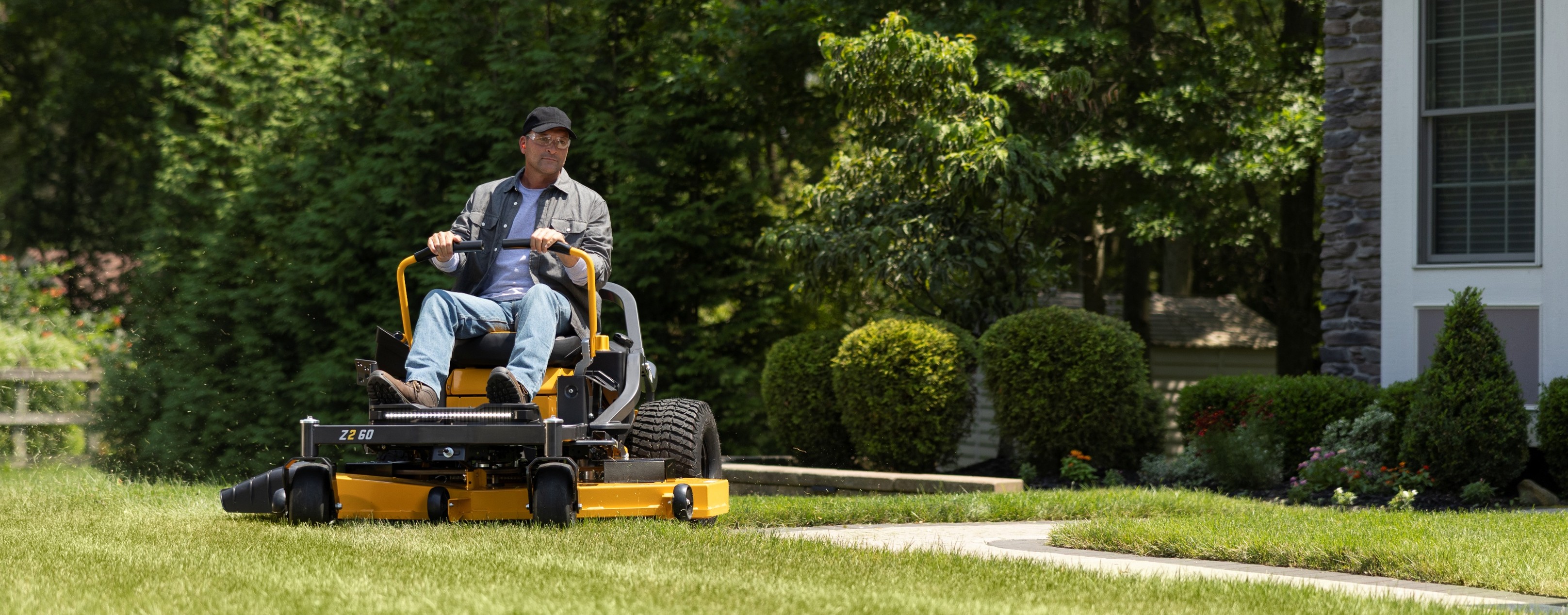man on cub cadet zero-turn mower cutting grass