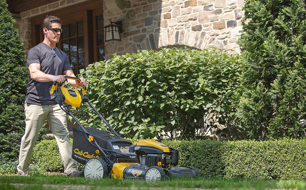 man cutting his lawn with walk-behind mower