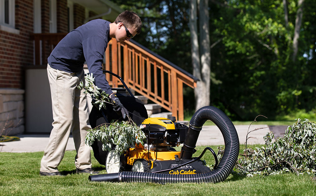 Man putting branches into Cub Cadet Shredder vacuum