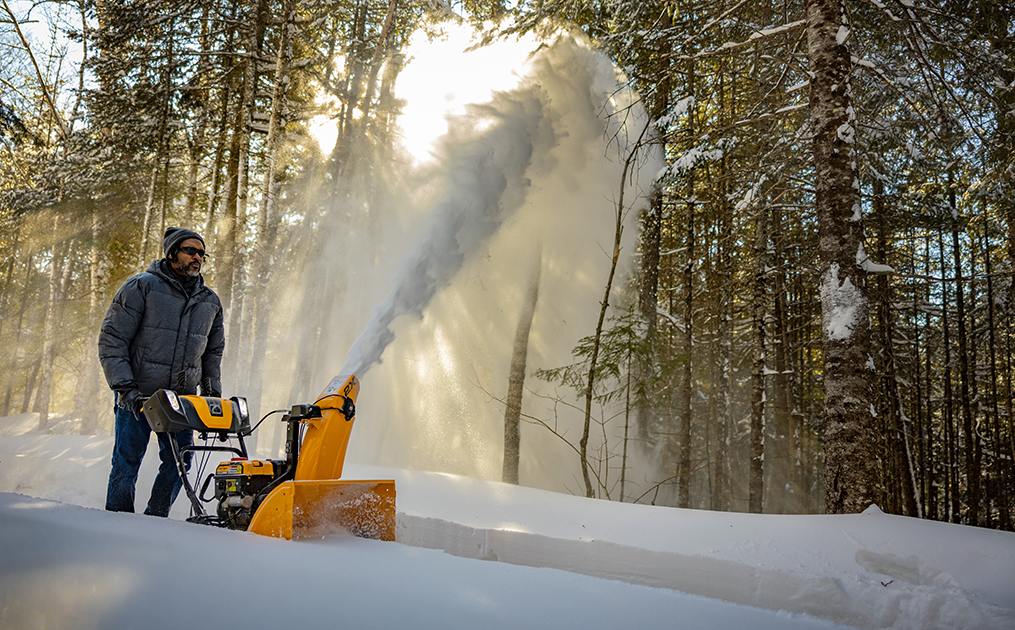 woman pushing snow blower in the snow