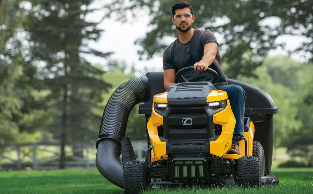 man riding lawn mower with bagger attachment